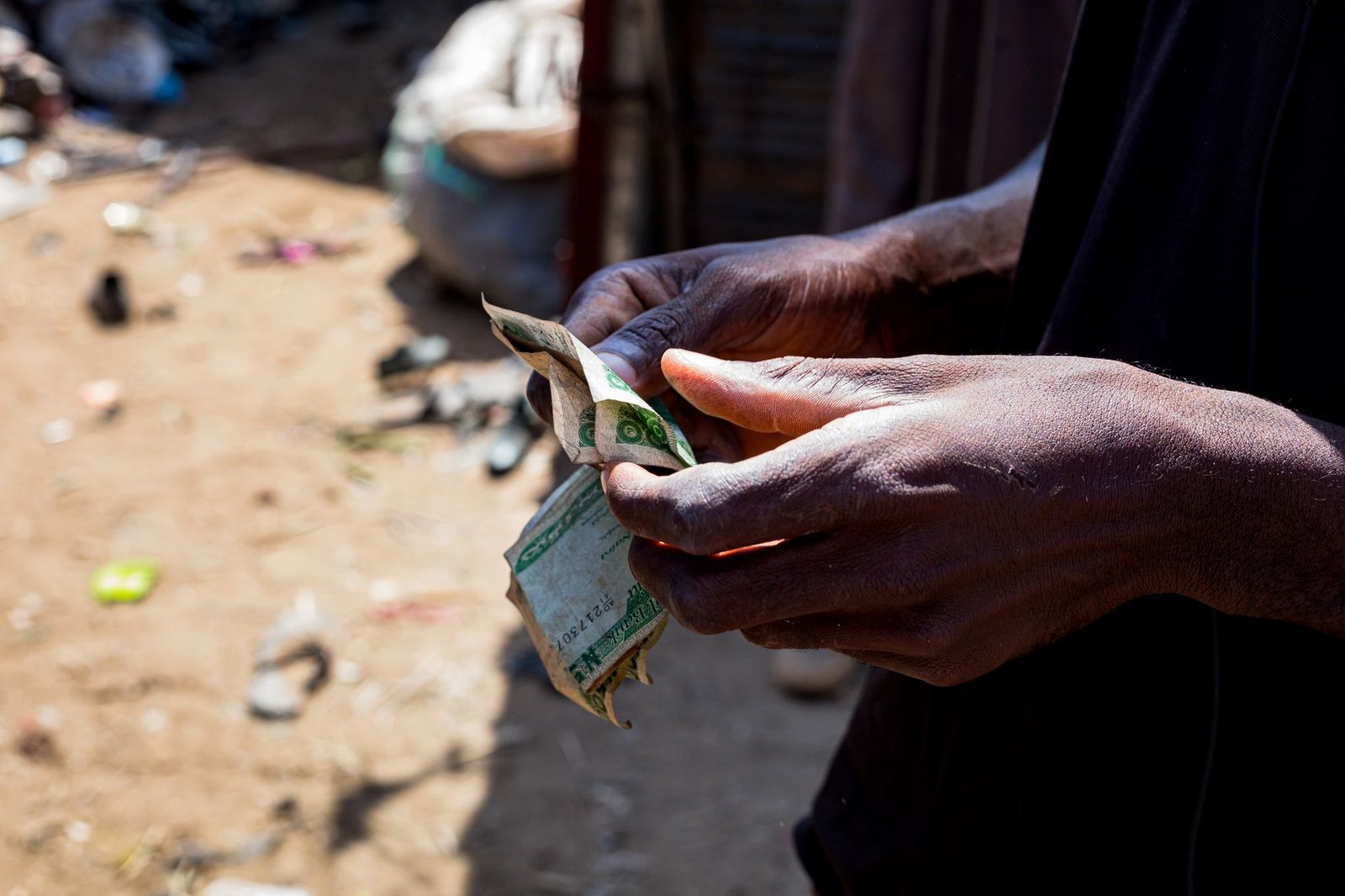 Detailed view of hands counting Nigerian naira outdoors, signifying economic activity.