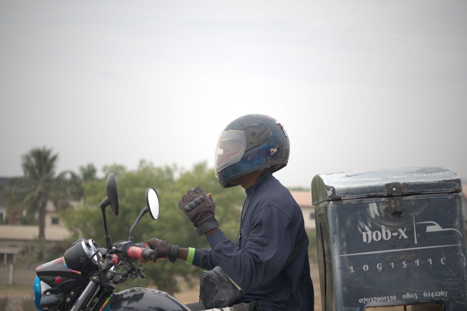 Delivery rider on a motorcycle in Nigeria, wearing protective gear and helmet