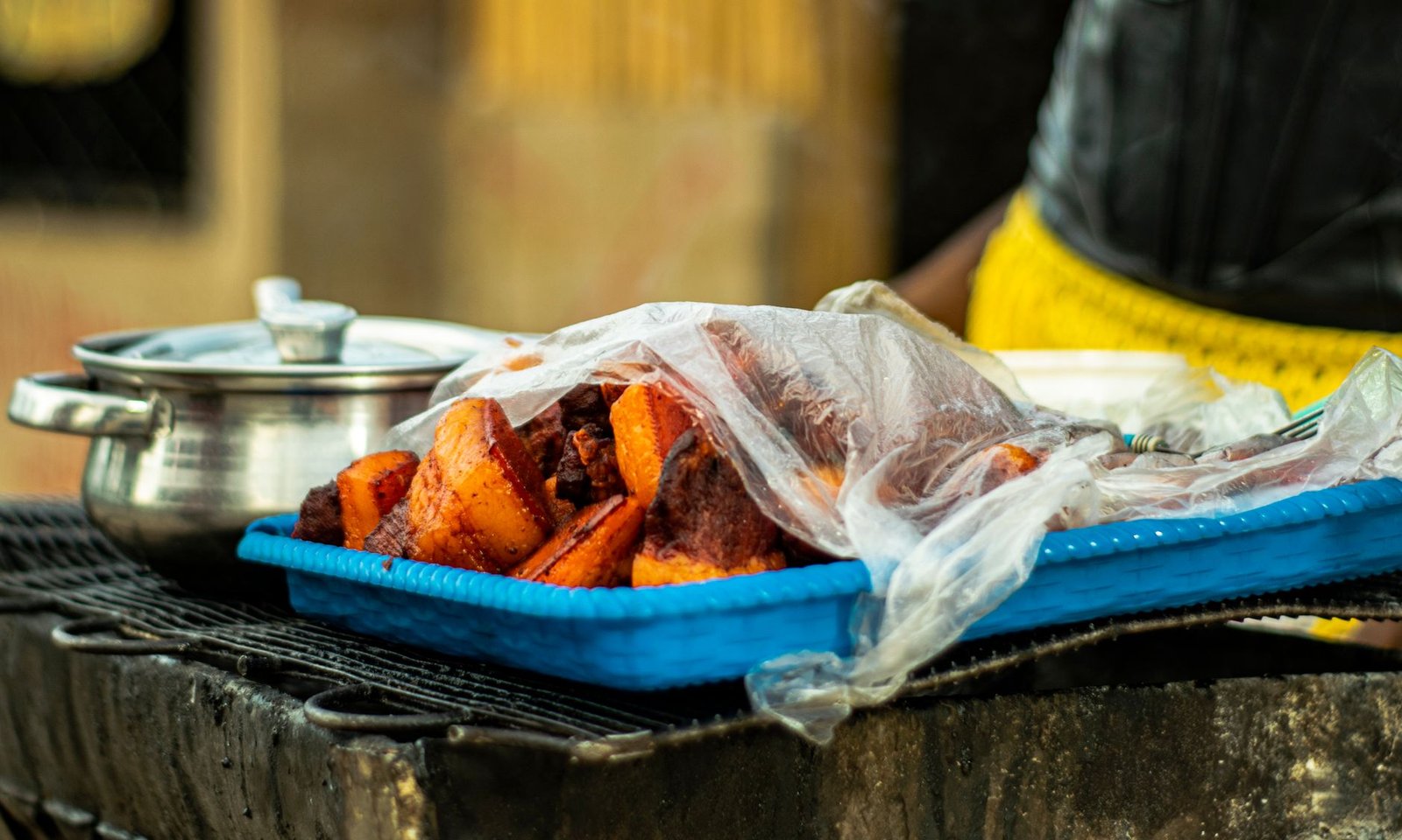 Close-up of grilled yams in a street food setting, showcasing vibrant colors and traditional methods.