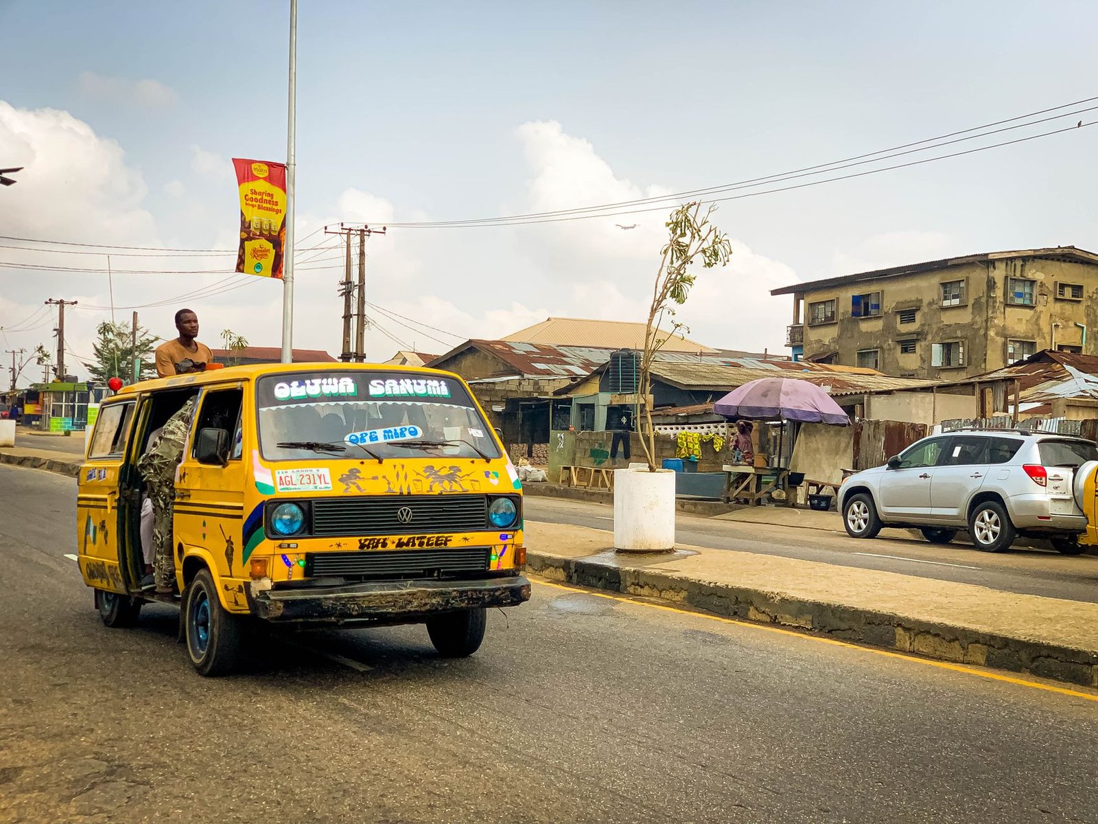 Vibrant street scene featuring a yellow danfo bus in Lagos, Nigeria during the day.