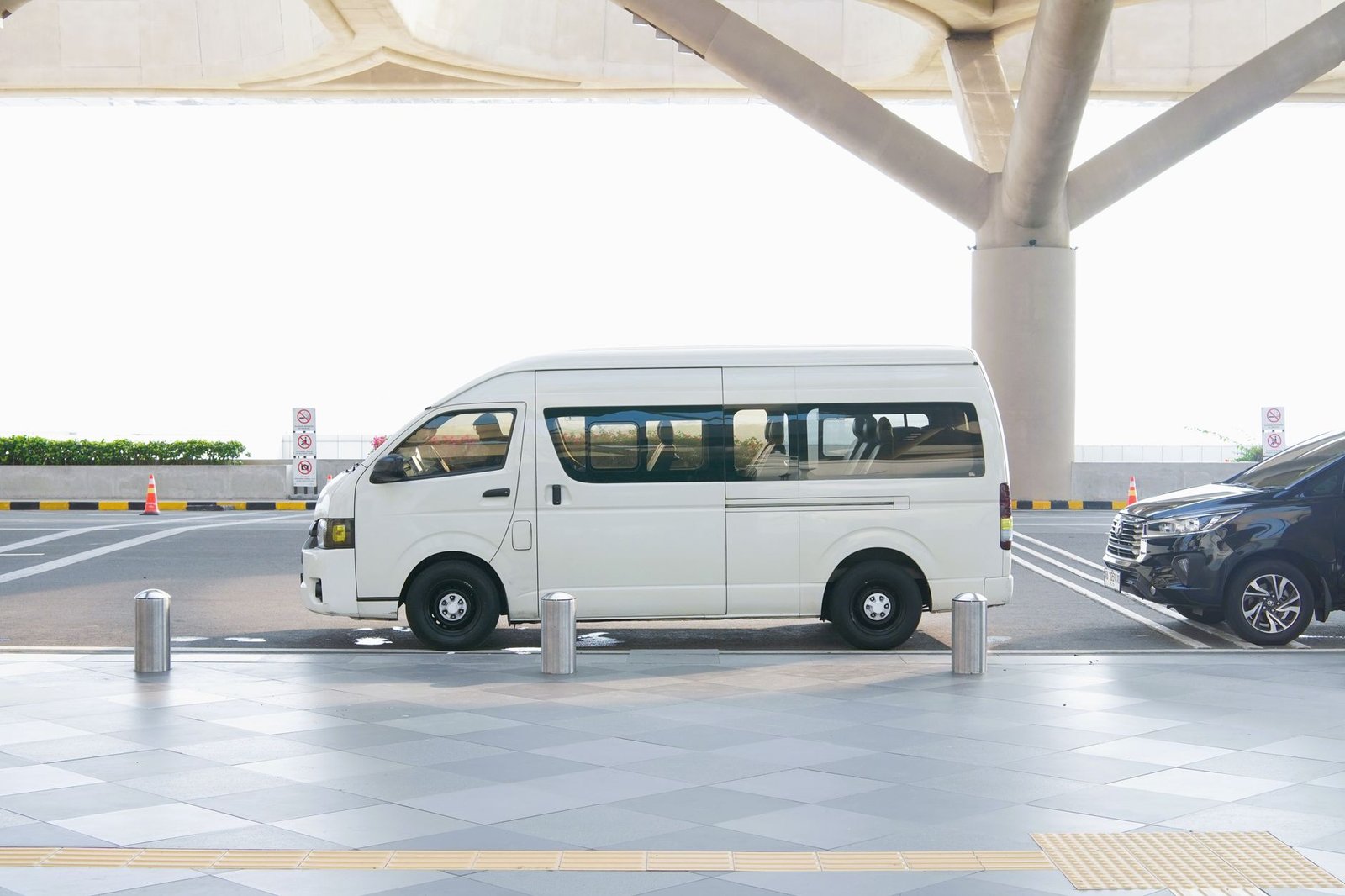 White minivan at an airport terminal drop-off zone