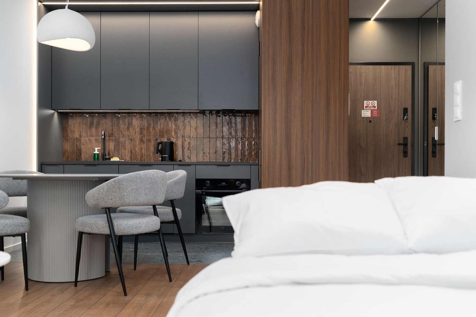 Stylish modern apartment interior featuring a compact kitchen, dining area, and cozy bedroom setup.