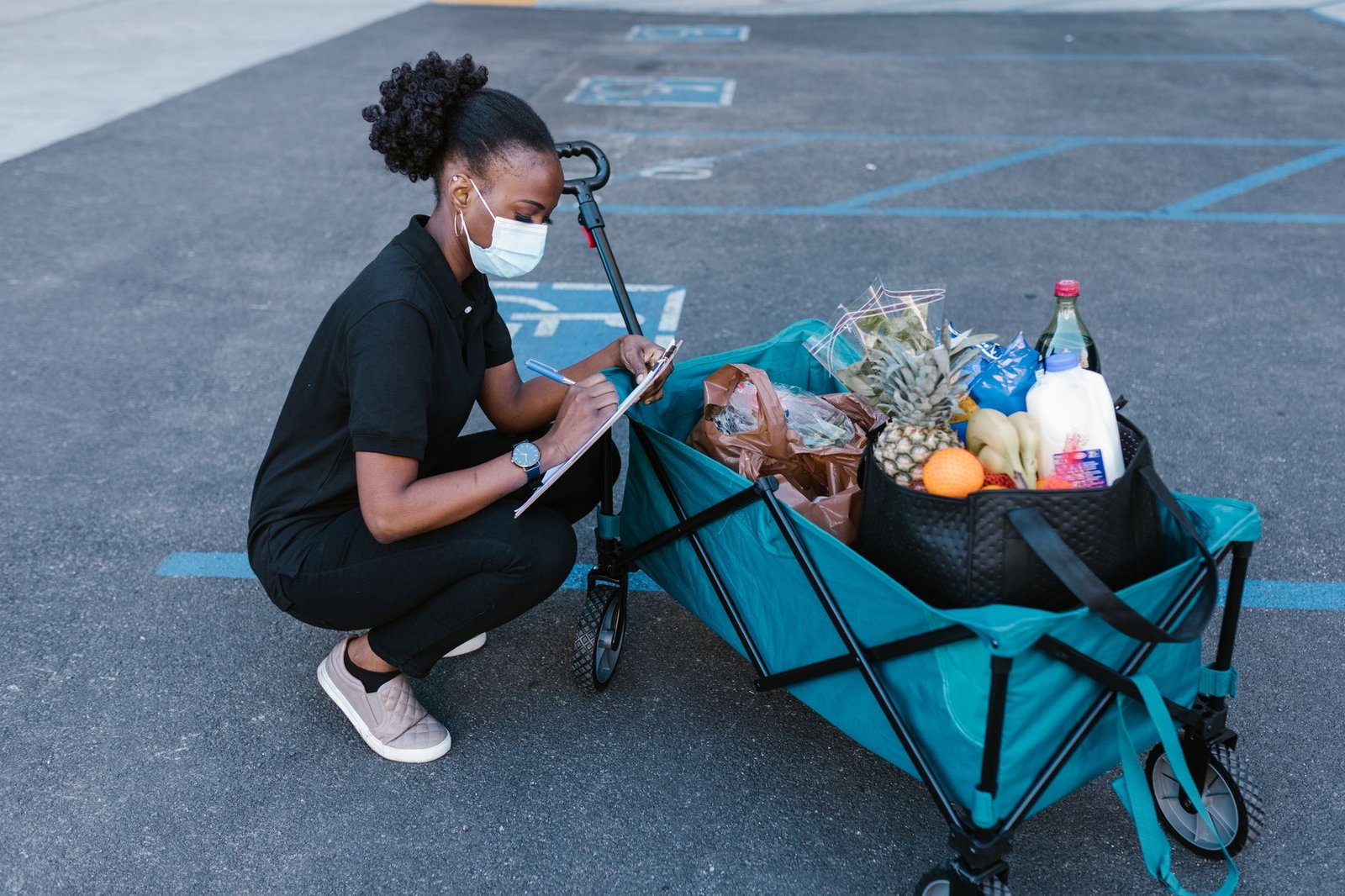 Woman checking a clipboard next to a delivery cart
