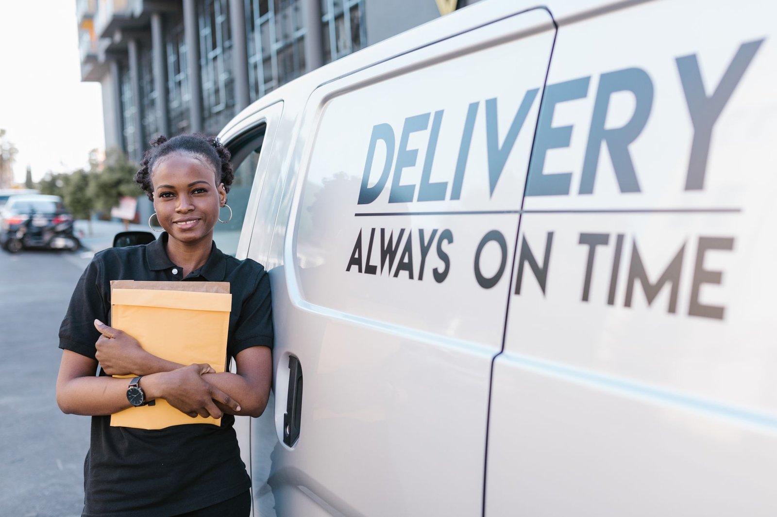 Smiling delivery woman with envelope by van