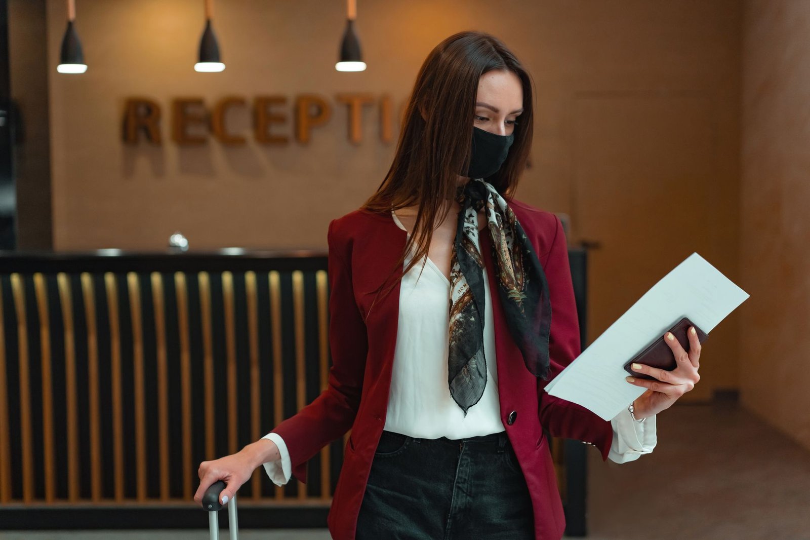 Woman at hotel reception with luggage and documents