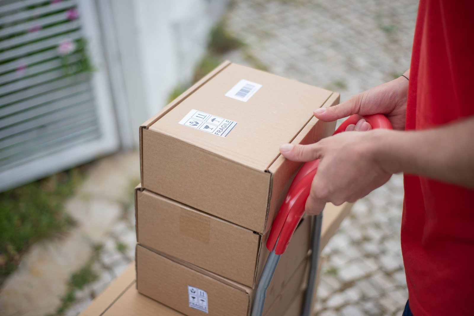 Hands moving stacked cardboard boxes on a trolley