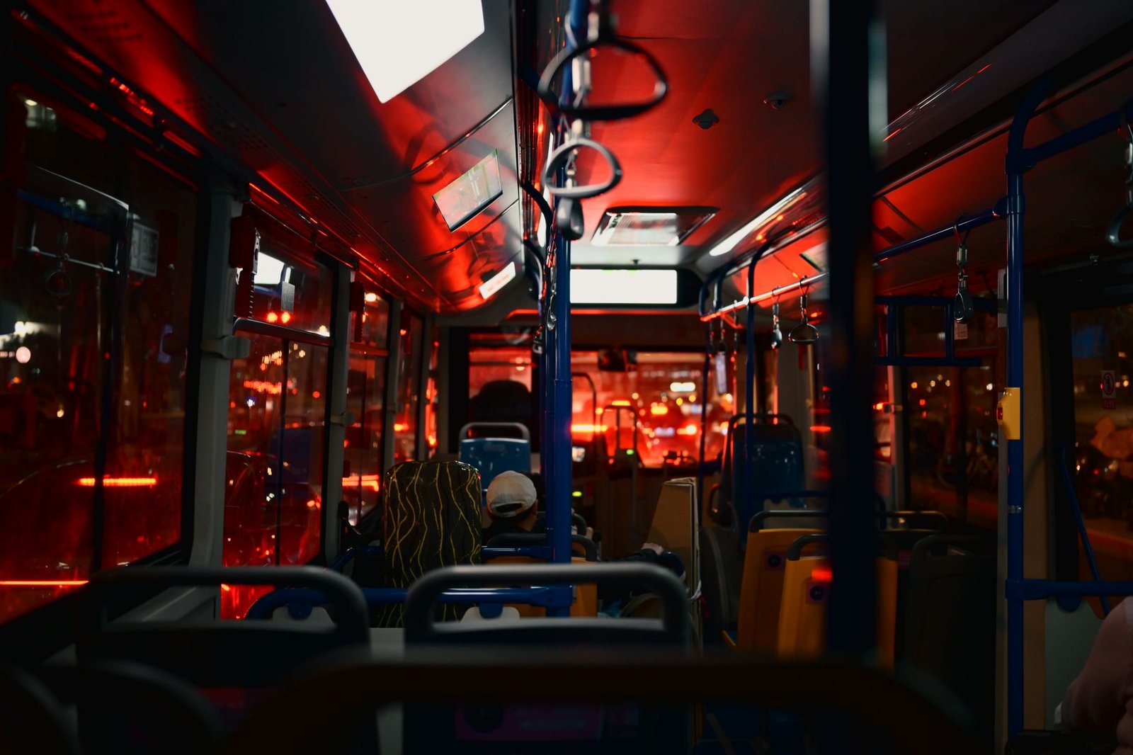 Nighttime city bus interior with passengers, illuminated by red lights