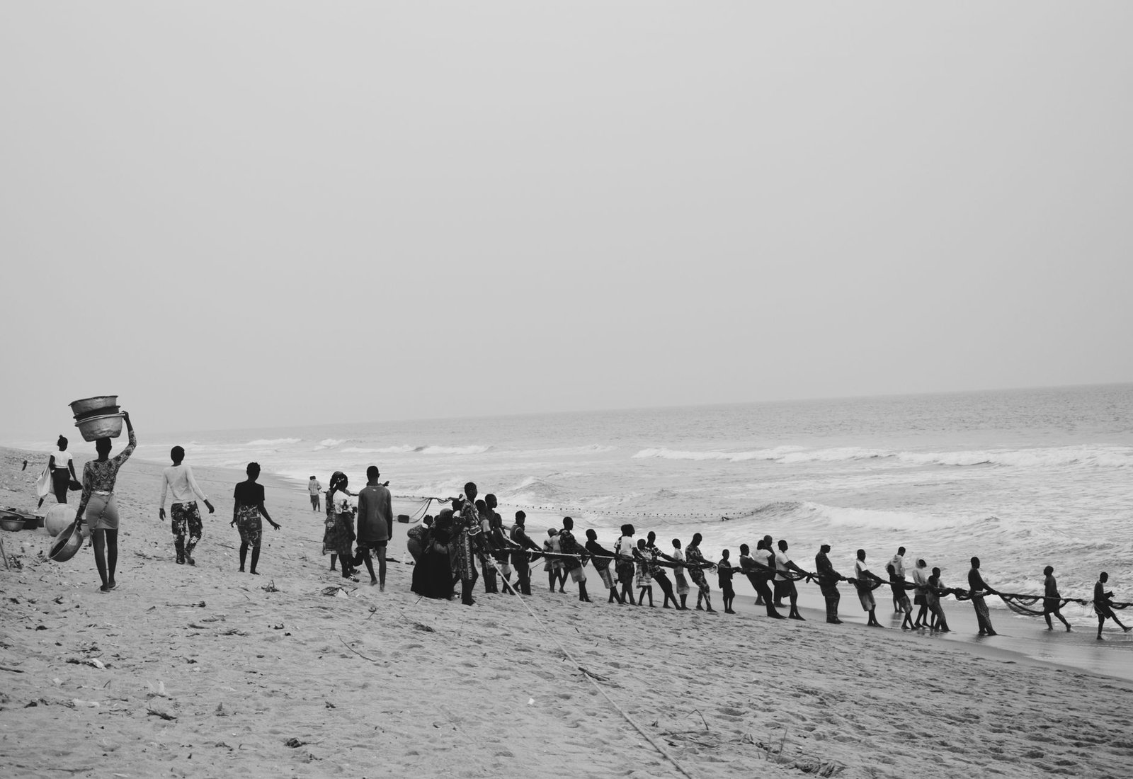 Adults engaging in communal fishing on Badagry Beach, Nigeria.
