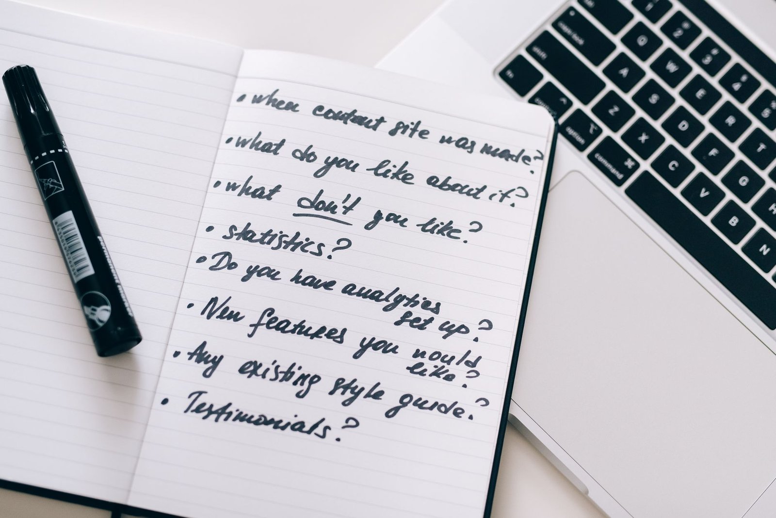 notebook with handwritten notes next to a laptop