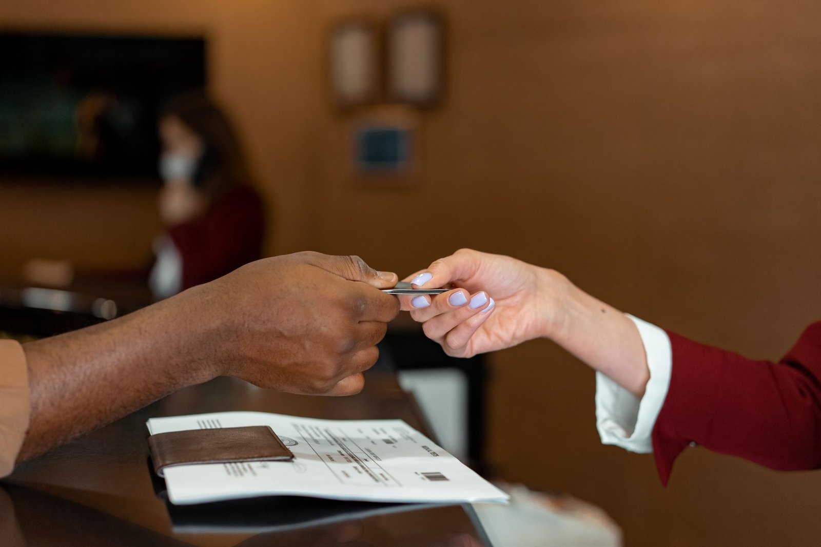 Hotel receptionist receiving a credit card from a guest during check-in